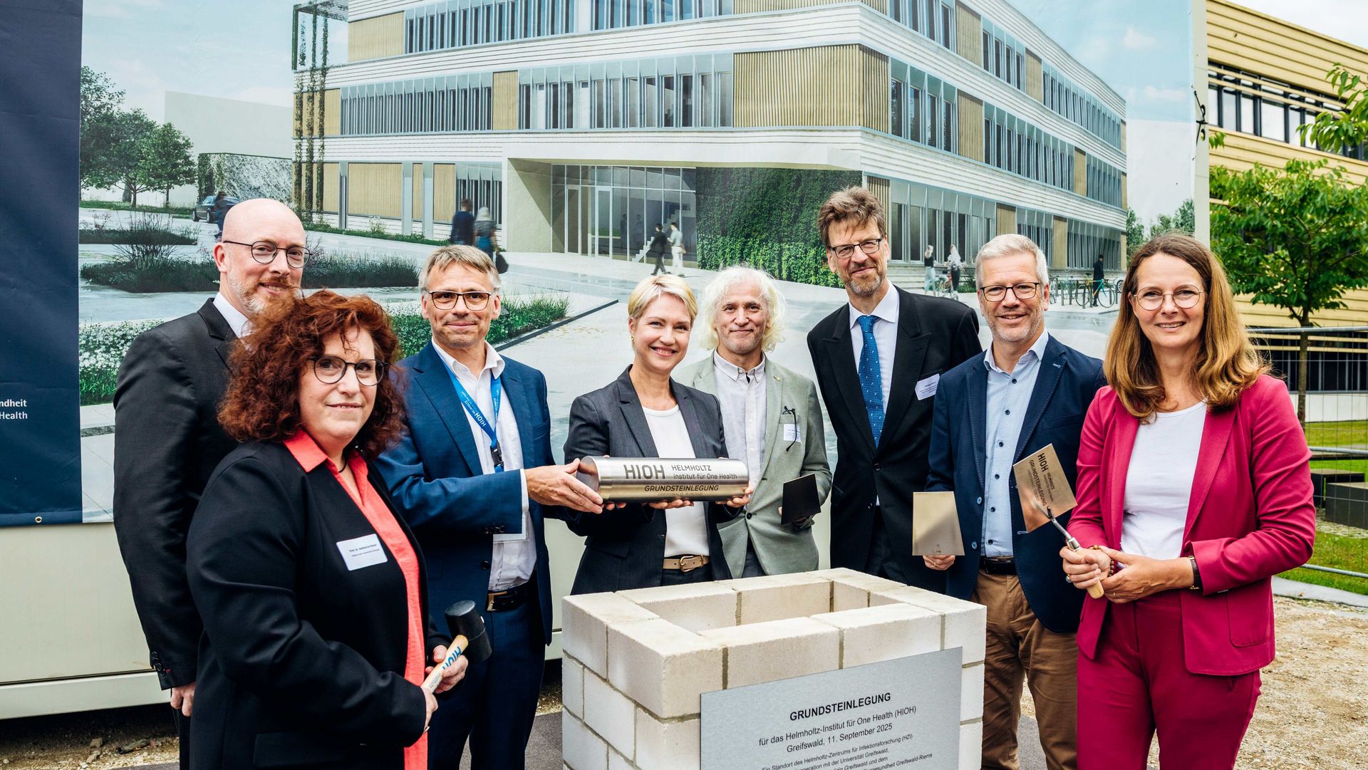 Group photo of eight persons behind a foundation stone